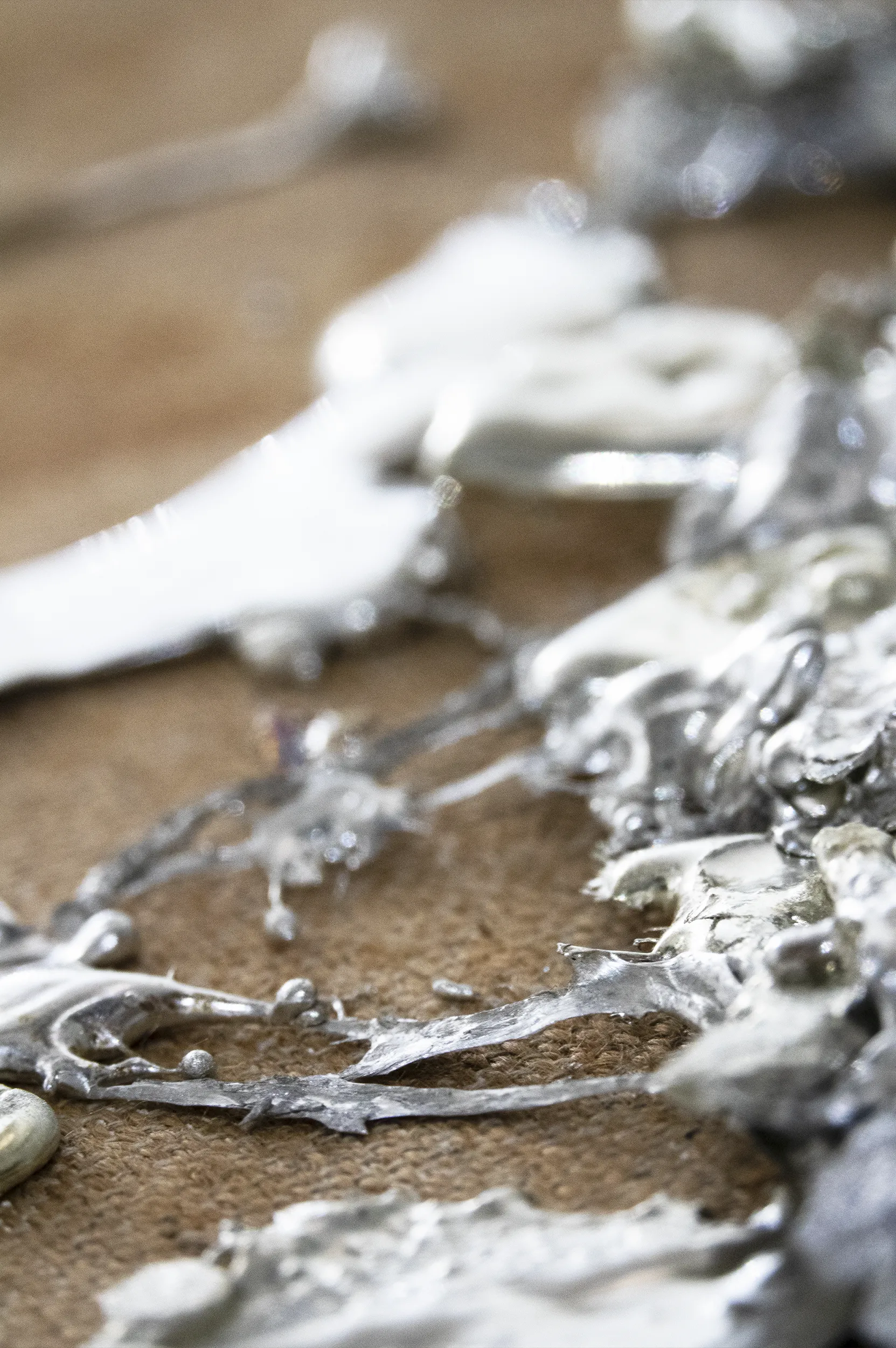 An close up detailed view of ‘Devoid III’ (2020) by Damian Boylan. A painting from his Elements Paintings series using molten rare earth indium metal on a course hessian canvas.