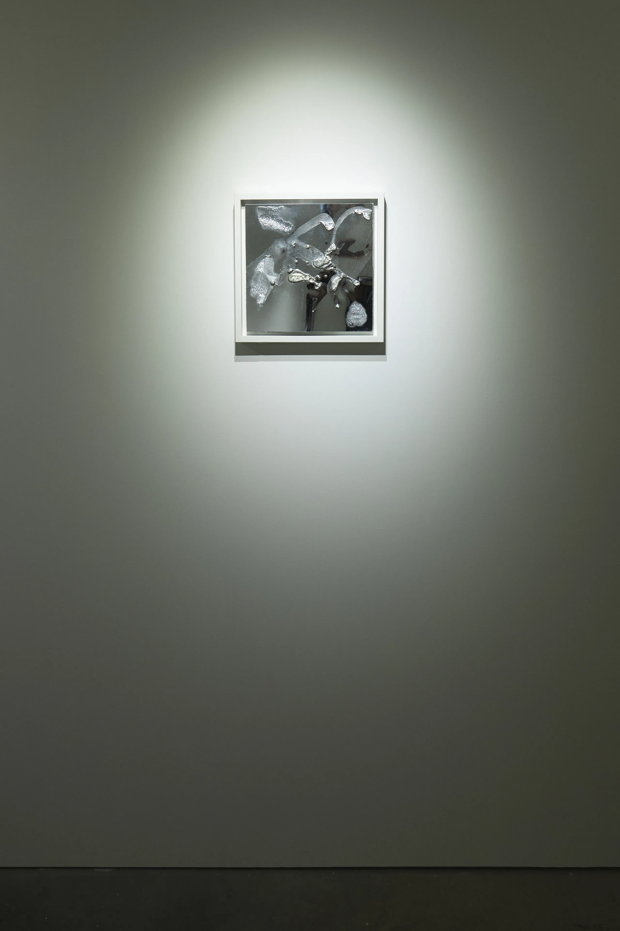 An Installation view of ‘Volition’ (2021) by Damian Boylan. A painting from his Elements Paintings series using molten indium metal bursting onto a silver mirrored poly(methyl methacrylate) canvas.