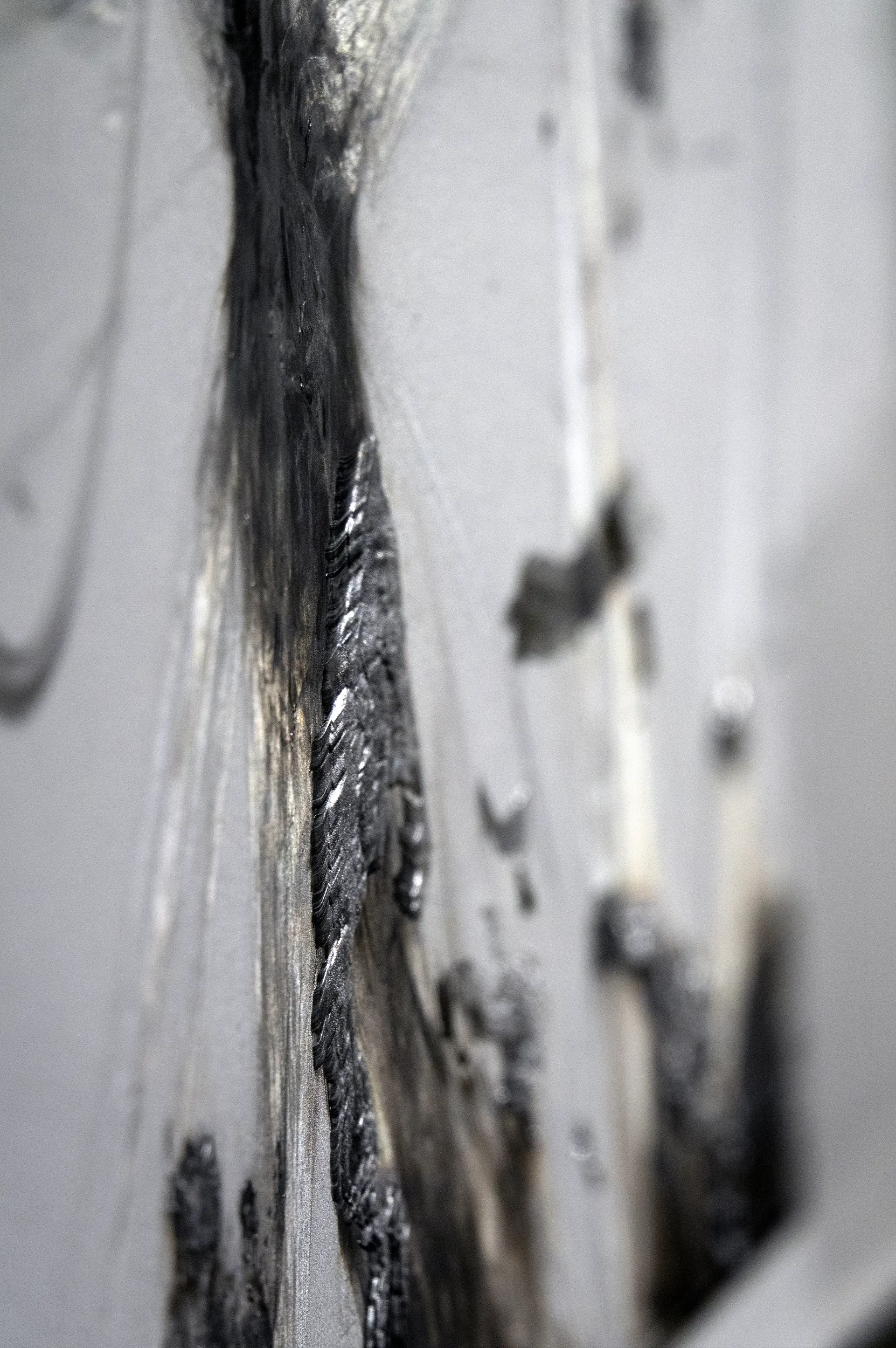 An detailed view of a Rarefaction painting from artist Damian Boylan's Rarefactions series, showing molten brass leaving an iridescent residual mark on a poly(methyl methacrylate) canvas.